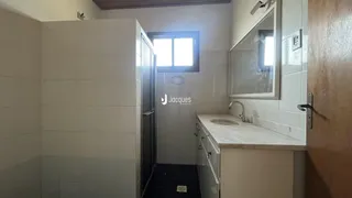Hall de entrada com revestimento de cerâmica branca e porta de madeira.