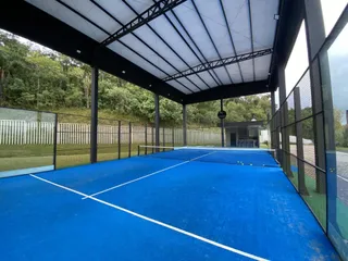 Uma quadra esportiva externa azul coberta com estrutura metálica.