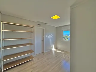 Uma sala de estar com piso de madeira clara e estantes embutidas.