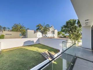 Um jardim gramado com muro branco e grade de vidro é visível na área externa da propriedade.