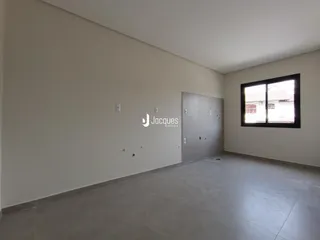 Vista interna de um ambiente com paredes brancas e piso de concreto.