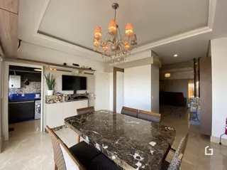 Ambiente interno com mesa de mármore e lustre em sala de jantar.