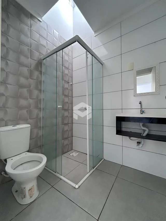 Foto de um banheiro com box de vidro e revestimento branco.