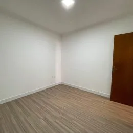 Foto de um corredor com piso de madeira e paredes brancas.