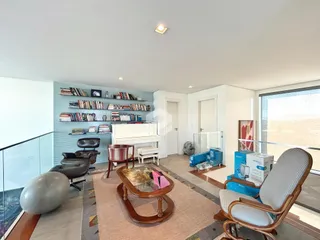 Ambiente interno de uma sala com estantes e assentos.