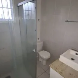 Foto de um banheiro com box de vidro e vaso sanitário.