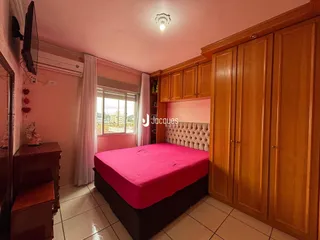 Quarto com cabeceira estofada e armários de madeira em um imóvel em Lajeado.