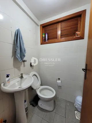 A foto mostra o interior de um banheiro com azulejos brancos.
