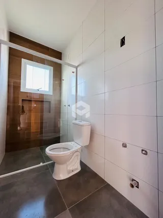 Foto de um banheiro com revestimento cerâmico e vaso sanitário branco.