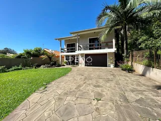 Vista da fachada de uma residência com jardim e entrada pavimentada.