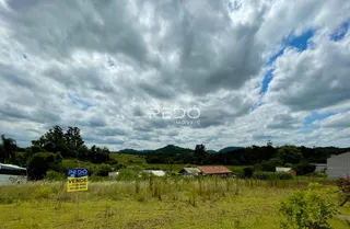Paisagem de campo com colinas ao fundo sob um céu nublado.