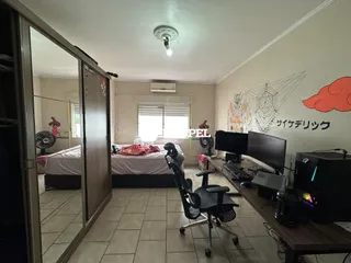 Quarto com cama e estação de trabalho em um ambiente interno.