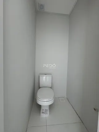 Corredor interno de um imóvel com um vaso sanitário branco.