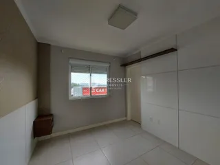 Ambiente interno de uma sala com piso de cerâmica clara e paredes neutras.