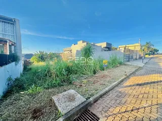 Vista externa de uma propriedade com vegetação e calçada no primeiro plano.