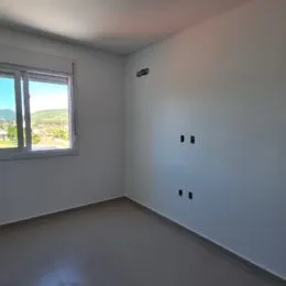 Foto de um cômodo interno com paredes brancas e uma janela.
