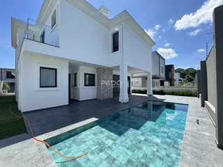 Fachada de casa branca com piscina e área externa.