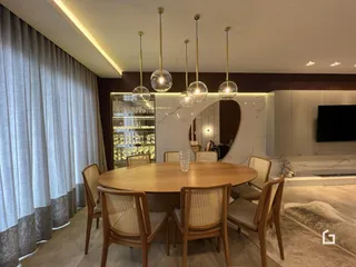Uma sala de jantar com mesa de madeira e iluminação pendente.