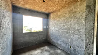 Interior de um cômodo com paredes de concreto aparente e piso cru.