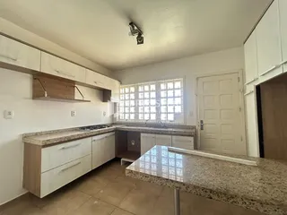 Foto de uma cozinha com armários brancos e bancadas de granito.