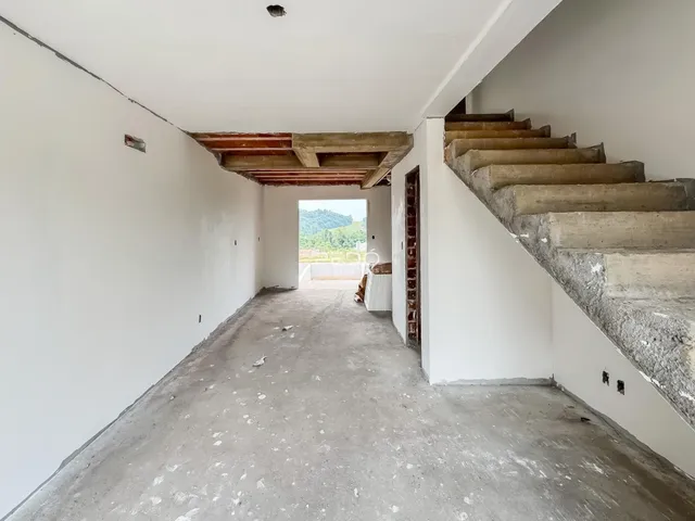 Corredor com piso de concreto e escadaria em um interior em construção.