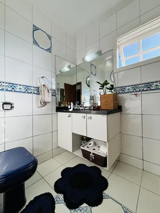 Foto de um banheiro com revestimento de azulejos brancos e detalhes azuis.