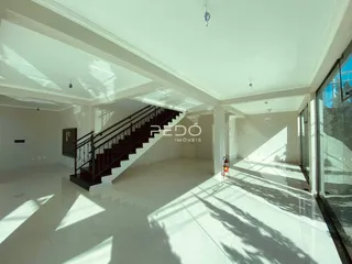 Interior de um espaço com escadaria e grandes janelas.