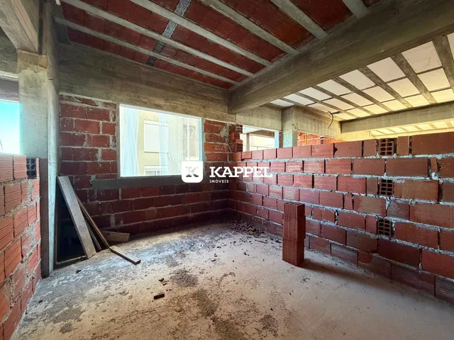 Interior de uma sala com paredes de tijolo aparente e estrutura de vigas exposta.