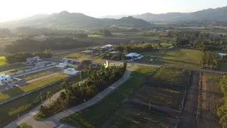 Vista aérea de uma propriedade rural com campos e estradas no horizonte.
