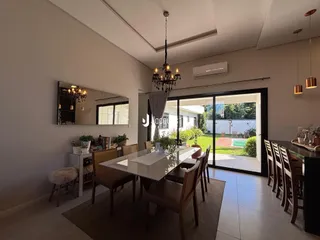 Sala de jantar com mesa de vidro e vista para o quintal.