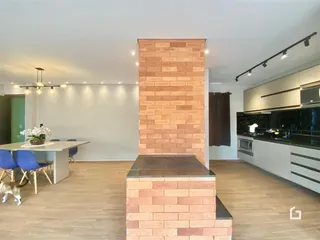 Ambiente de sala de estar com parede de tijolos aparentes e cozinha moderna.