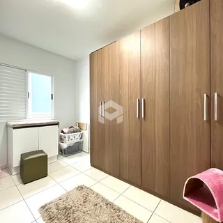 Quarto com armário de madeira grande e piso de cerâmica branca.