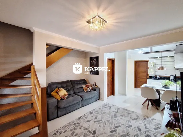 Sala de estar com sofá e escadaria em um apartamento em Lajeado.