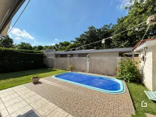 Foto da piscina e área externa com paisagismo ao lado de um muro.
