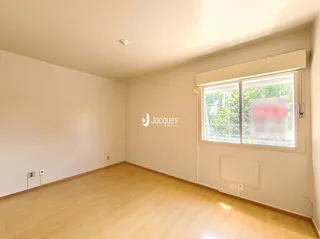 Ambiente interno de uma sala com piso de madeira clara e paredes brancas.