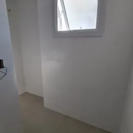 Vista de uma parede branca com uma janela em um ambiente interno.