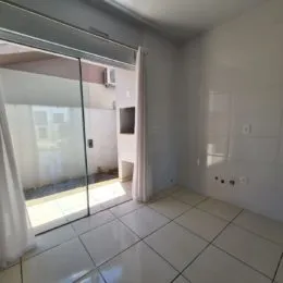 Vista interna de uma sala com piso de cerâmica e porta de vidro.