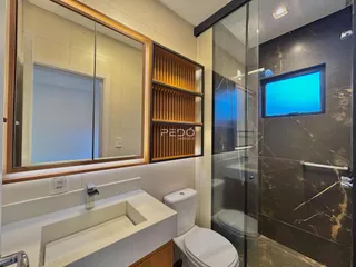 Banheiro moderno com box de vidro e revestimento de mármore escuro.