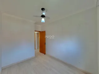 Ambiente interno de uma sala com piso de madeira clara e parede branca.