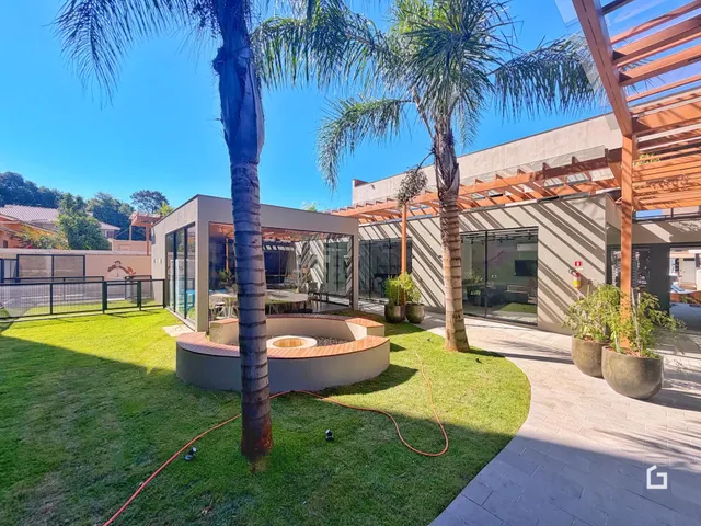 Fachada de uma residência em Lajeado, Brasil, com jardim e palmeiras.