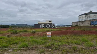 Vista externa de uma propriedade com terreno gramado e estruturas ao fundo.