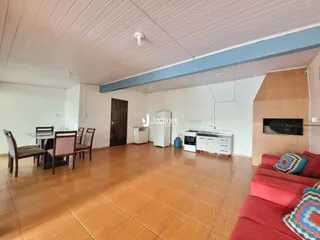 Ambiente interno de sala de jantar e cozinha com piso de madeira.