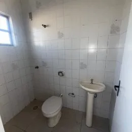 Foto interna de um banheiro com revestimento de azulejos brancos.