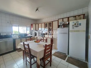 Uma sala de jantar com mesa de madeira e piso cerâmico.