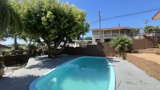 Foto de uma piscina em um quintal com vegetação ao fundo.