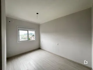 Ambiente interno de uma sala com piso de madeira clara e janela com vista para a paisagem.