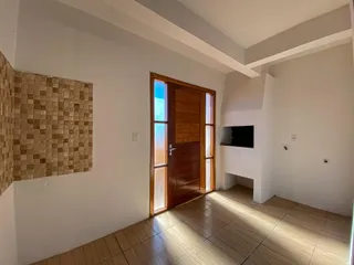 Sala de estar com porta de madeira e piso de cerâmica iluminada pela luz natural.
