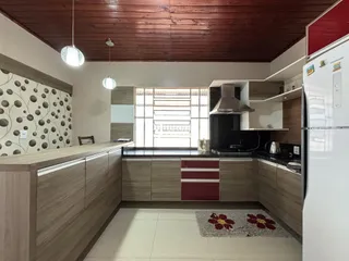 Vista da cozinha e sala de jantar com armários modernos e piso claro.