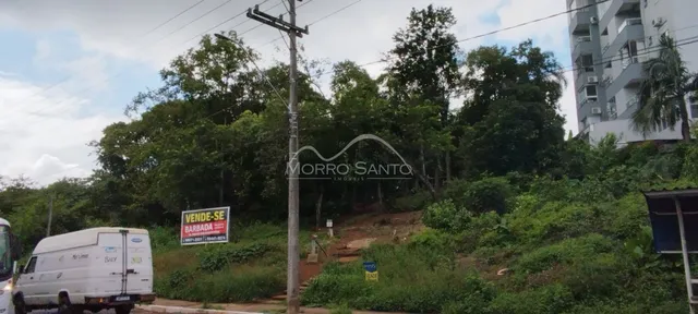 Vista externa de uma propriedade com vegetação densa e sinalização de venda.