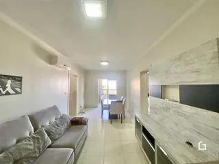 Sala de estar com cozinha visível em um apartamento.